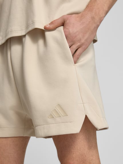 Männermodel trägt Regular Fit Sweatshorts mit Modal und Baumwoll-Anteil von adidas Sportswear in Optik: Unifarben, Logo-Detail, Bundabschluss: elastisch mit Tunnelzug, seitliche Eingrifftaschen, Material-Mix mit Modal und Baumwoll-Anteil, Nahaufnahme Oberschenkel.