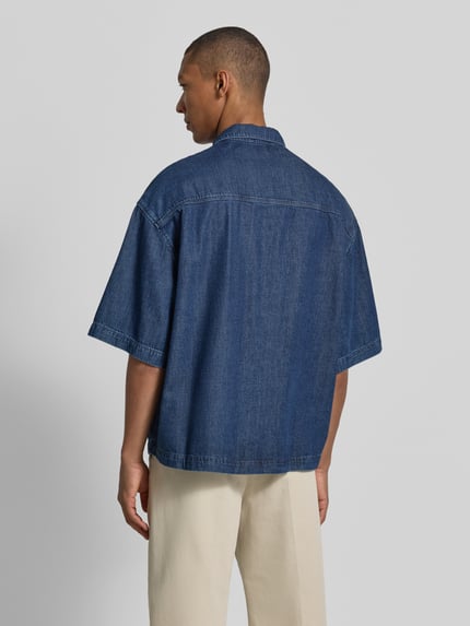 Mannelijk model draagt Oversized Jeanshemd aus Baumwoll-Lyocell-Mix van Armedangels in denimlook, mix van katoen en lyocell, achterpas, gestikt logo, oversized fit, kentkraag, borstzak, twill. Ganzkörperansicht Rückansicht.