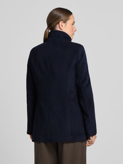 Frauenmodel trägt Jacke mit Stehkragen und Eingrifftaschen von FUCHS SCHMITT in Dunkelblau, Material-Mix mit Woll-Anteil, Ganzkörperansicht Rückansicht.