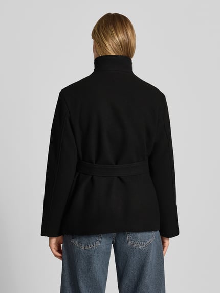 Frauenmodel trägt Jacke mit Stehkragen und Bindegürtel von REVIEW in Schwarz, Material-Mix mit Viskose-Anteil, Ganzkörperansicht Rückansicht.