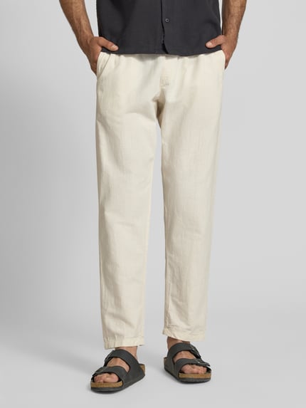 Männermodel trägt Relaxed Fit Hose aus Baumwoll-Leinen-Mix Modell 'KANE' von Jack & Jones in Beige, sichtbare Struktur, lockere Passform, elastischer Bund mit Tunnelzug und Gesäßtasche, Bundweite bei Größe M: 41 cm, Innenbeinlänge 77 cm, Ganzkörperansicht von vorne.