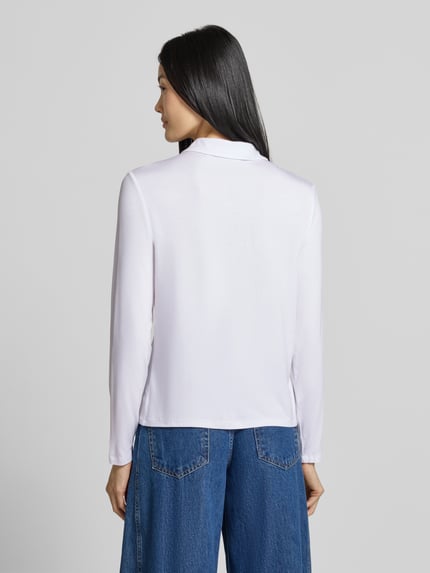 Frauenmodel trägt Slim Fit Hemdbluse aus Viskose-Mix von COMMA in Weiß mit Hemdblusenkragen und langen Ärmeln, Ganzkörperansicht Rückansicht.