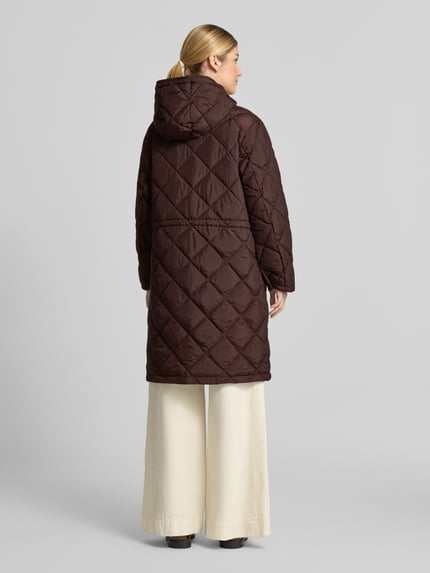 Frauenmodel trägt Steppmantel mit Kapuze Modell 'Olga' von FREE/QUENT in Dunkelbraun mit Rautensteppung, Ganzkörperansicht Rückansicht. Damen Steppmantel, Regular Fit, Knopfleiste, Rückenlänge 98 cm, Schulterbreite 47 cm, Brustweite 55 cm, Ärmellänge 60 cm.