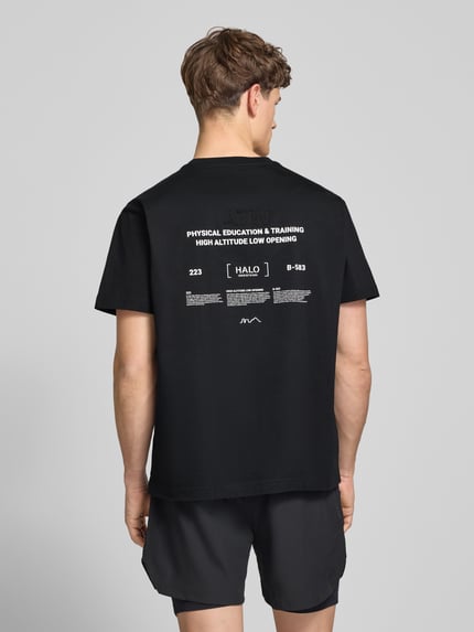 Männermodel trägt schwarzes T-Shirt mit weißem Label-Print von HALO, reine Baumwolle, Regular Fit, Rundhalsausschnitt, Ganzkörperansicht Rückansicht.