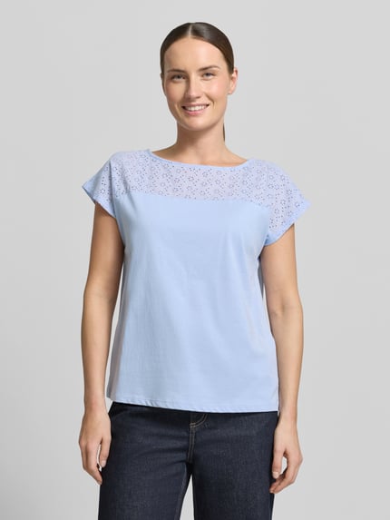 Vrouwenmodel draagt Regular Fit Blusentop uit pure katoen model 'JANNI' van Vero Moda in effen lichtblauw met semitransparante inzet en boothals, korte mouw, gladde jerseystructuur, vooraanzicht van het hele lichaam.