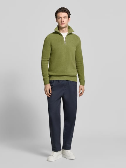 Männermodel trägt Pullover mit Troyerkragen von MARC O’POLO in Grün, Strukturstrick, Regular Fit, Reißverschluss, Ganzkörperansicht von vorne.