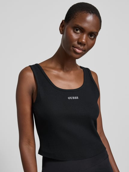 Vrouwenmodel draagt Slim Fit Top met Logo-Stitching model 'Circe' van Guess Activewear, elastische katoenmix, zwart met ribstructuur, ronde hals, vooraanzicht bovenlichaam