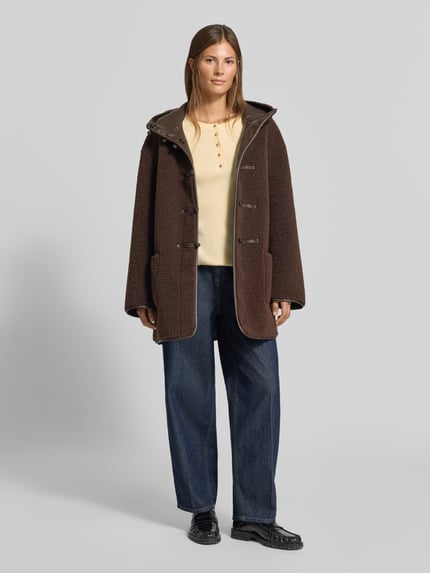 Frauenmodel trägt Slim Fit Longsleeve aus Strick-Optik von MYON, beige, mit Knopfleiste und Rundhalsausschnitt, Ganzkörperansicht von vorne. Rückenlänge bei Größe 36 etwa 60 cm, Ärmellänge etwa 66 cm.