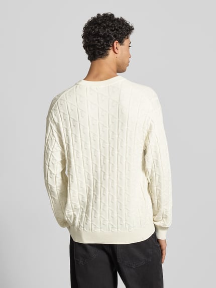 Männermodel trägt Strickpullover mit Rundhalsausschnitt Modell 'EASY' von Calvin Klein Jeans, cremefarben, Baumwolle, Ganzkörperansicht Rückansicht.