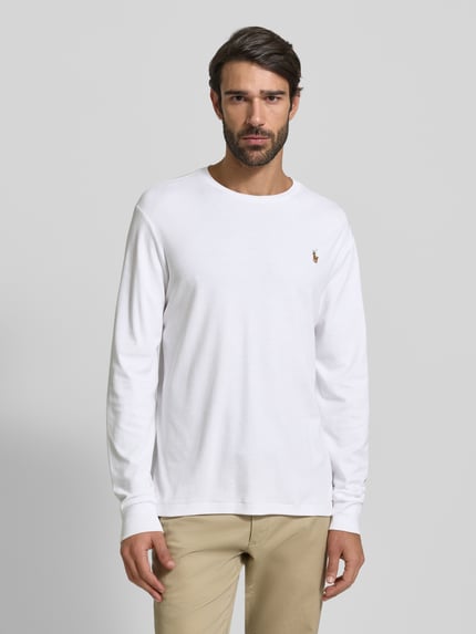 Męski model nosi Bluzkę z długim rękawem z prążkowanymi wykończeniami od Polo Ralph Lauren z bawełny, krój regular fit, okrągły dekolt, wyhaftowane logo, długość tyłu w rozmiarze M: 68 cm, kolor biały, gładka tekstura. Ganzkörperansicht von vorne.