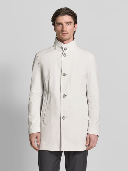 Männermodel trägt Regular Fit Mantel mit Stehkragen Modell 'FYNN' von Strellson in Unifarbe, glatte Twill-Textur, Ganzkörperansicht von vorne.