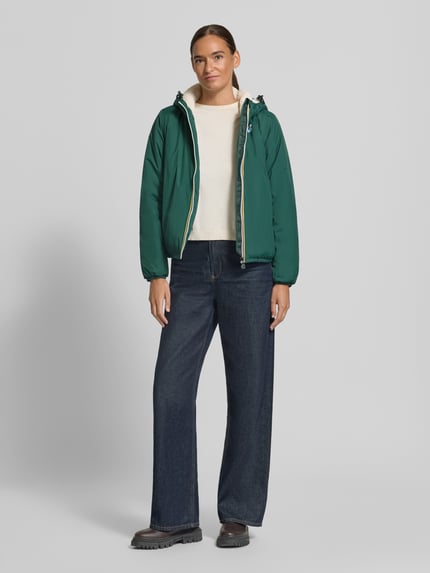 Frauenmodel trägt Regular Fit Jacke mit Logo-Print Modell 'CLAUDETTE' von K-WAY in Dunkelgrün, Kapuze, elastische Abschlüsse, Ganzkörperansicht von vorne.