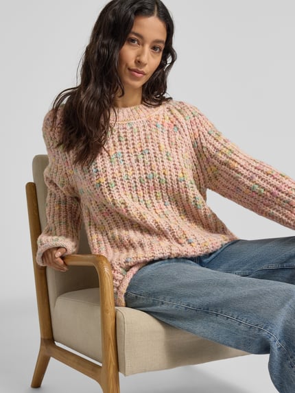 Kobieta nosi Strickpullover mit Rundhalsausschnitt und Rollsaum od Smith and Soul, grobstrick, efektowna przędza, różowe odcienie, regular fit, widok z przodu, ujęcie od pasa w górę.