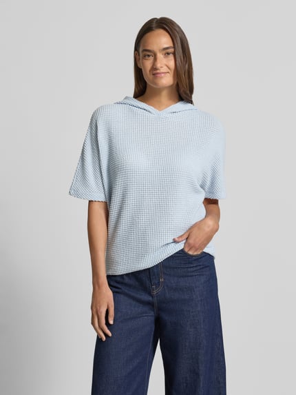 Modelka kobieca nosi Strickshirt mit Kapuze Modell 'Gikaria' od OPUS, jasnoniebieski, strukturalna dzianina, relaxed fit, bawełna, widok całej sylwetki z przodu.