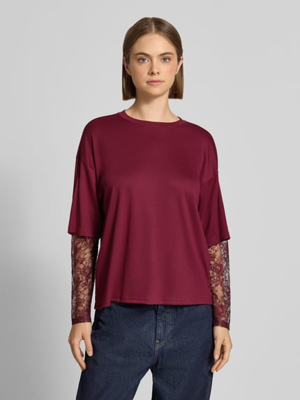 Frauenmodel trägt Regular Fit Langarmshirt mit Viskose-Anteil Modell 'TAHLIA' von ONLY in Dunkelrot mit Spitzenärmeln, Damen Langarmshirt von ONLY, Ganzkörperansicht von vorne.