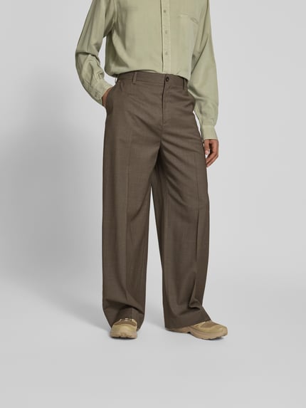 Mężczyznamodel nosi Wide Fit Stoffhose aus Woll-Mix von Filippa K, brązowy, kanty, tylne kieszenie, szerokość w rozmiarze 50: 80 cm, długość nogawki od wewnątrz 45 cm, krój wide fit, widok całej sylwetki z przodu.