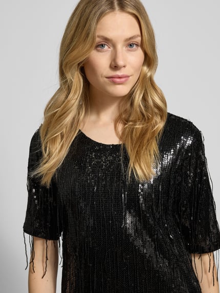 Frauenmodel trägt Knielanges Kleid mit Pailletten und Fransen von Milano Italy, Gerader-Schnitt, Rundhalsausschnitt, Nahaufnahme Oberkörper.