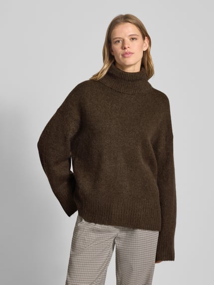 Vrouwenmodel draagt Oversized Strickpullover mit Rollkragen van Gina Tricot in bruin, geribde boorden, katoenmix, vooraanzicht van bovenlichaam.