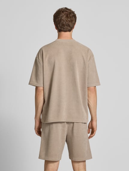 Männermodel trägt Oversized T-Shirt mit Logo-Stitching Modell 'Lagos' von Pegador aus Elastischer-Material-Mix in Beige, Oversized-Fit, Rückenlänge 65 cm bei Größe M, Ganzkörperansicht Rückansicht.