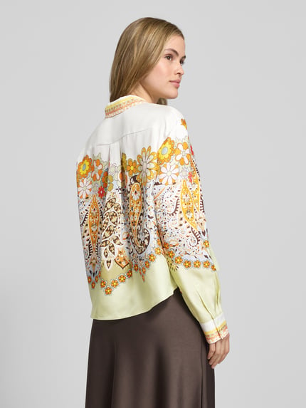 Modelka kobieca nosi Boxy Fit Bluse aus Satin im Allover-Look od Herzensangelegenheit, wzór kwiatowy, kolory żółty, biały, brązowy, widok z tyłu.