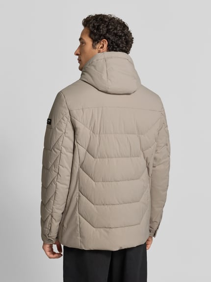 Mannelijk model draagt Steppjacke mit Zweiwege-Reißverschluss van bugatti in regular fit, beige, gewatteerd, rugaanzicht, context: herenjack met capuchon met tunnelkoord, ritssluiting, zijzakken, ruglengte 75 cm, schouderbreedte 49 cm, borstwijdte 60 cm, mouwlengte 67 cm. Ganzkörperansicht Rückansicht.