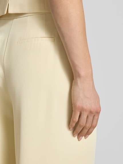 Kobiece modelka nosi Wide Leg Stoffhose mit Raffungen od Christian Berg Cocktail z elastycznej mieszanki materiałów, kolor jasny beż, marszczenia, zapięcie na haftkę i zamek błyskawiczny, szerokość w rozmiarze 36: 38 cm, długość wewnętrzna nogawki: 82 cm, zbliżenie na tył biodra