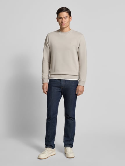 Męski model nosi Regular Fit Sweatshirt aus reiner Baumwolle Modell 'WESTART' od BOSS Orange, efekt: jednolity kolor, drobne prążkowanie, aplikacja z wyhaftowanym logo, okrągły dekolt, długi rękaw, elastyczne zakończenia, bawełna, Ganzkörperansicht von vorne.