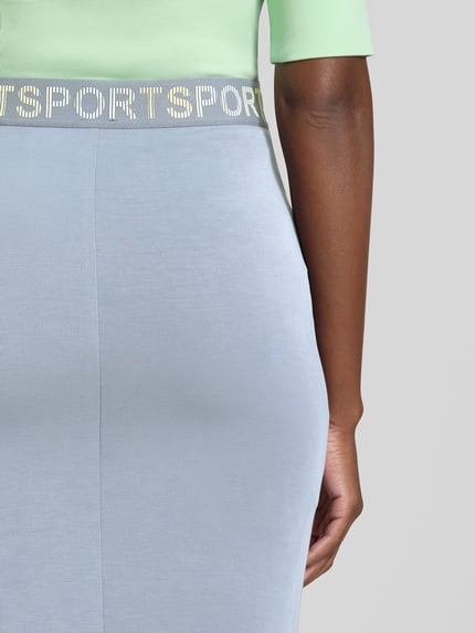 Frauenmodel trägt Midirock aus Lyocell-Mix von Marc Cain, hellblau, Statement-Print, elastischer Bund, Nahaufnahme Unterkörper.