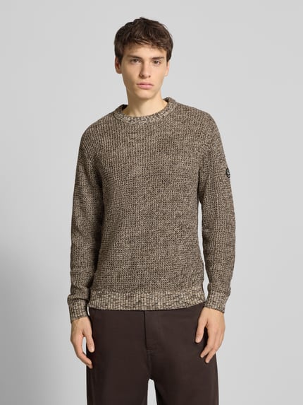 Männermodel trägt Strickpullover mit gerippten Abschlüssen Modell 'LIAM' von Jack & Jones, melierte Brauntöne, Regular Fit, Ganzkörperansicht von vorne.