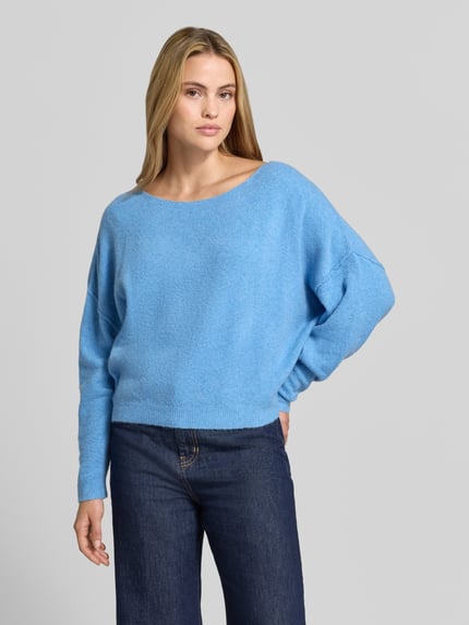 Frauenmodel trägt Relaxed Fit Strickpullover aus Material-Mix mit Leinen-Anteil von American Vintage in Hellblau mit gerippten Abschlüssen, überschnittenen Schultern, Langarm und Rundhalsausschnitt, kombiniert zu dunkler Jeans; Damen Strickpullover Modernes Design, Ganzkörperansicht von vorne.