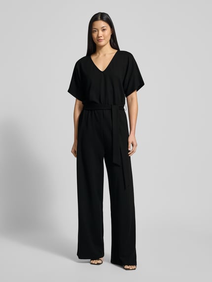 Kobiece modelka nosi czarny Jumpsuit z wiązanym paskiem model 'Renata' od GUIDO MARIA KRETSCHMER WOMAN, materiał z wiskozą i streczem, luźny krój, V-dekolt, widok całej sylwetki z przodu.