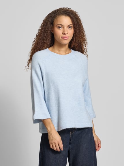Vrouwenmodel draagt Oversized Strickpullover mit 3/4-Arm Modell 'SIMONI' van Only in lichtblauw melange, unie en grof gebreid, oversized fit, geribde zoom en mouwuiteinden, ronde hals, detailopname bovenlichaam, vooraanzicht.