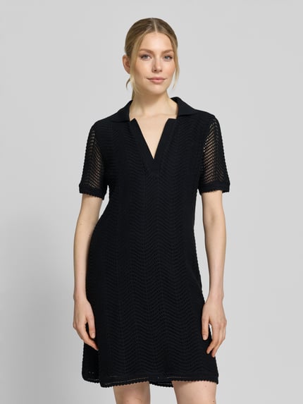 Modelka nosi Leicht ausgestelltes Häkelkleid aus Baumwoll-Mix Modell 'C_ELOA' von BOSS Orange, efekt: jednolity kolor, krój: lekko rozkloszowana, długość mini, kształt kołnierza: kołnierzyk polo, dekolt: dekolt w serek, halka pod sukienkę, szydełkowa koronka, rękaw: krótki rękaw, prosty dół, mieszanka bawełny, Ganzkörperansicht von vorne.