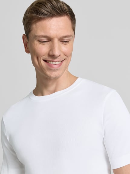 Männermodel trägt weißes Herren T-Shirt mit Rundhalsausschnitt Modell 'ENIL' von Drykorn, Reine Baumwolle, Slim Fit, Nahaufnahme Oberkörper.