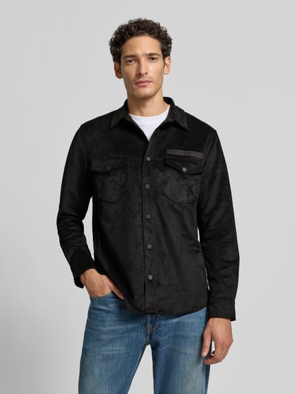 Männermodel trägt Oversized Hemdjacke mit Logo-Stitching Modell 'Ekel' von HUGO in Schwarz, weiche Struktur, Jeans, Herren Hemdjacke, Ganzkörperansicht von vorne.