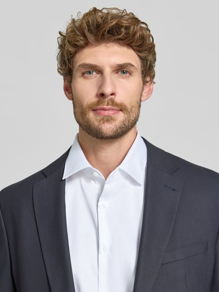 Männermodel trägt Regular Fit Businesshemd aus reiner Baumwolle von Seidensticker, weiß, Kentkragen, Nahaufnahme Oberkörper, Knopfleiste sichtbar.