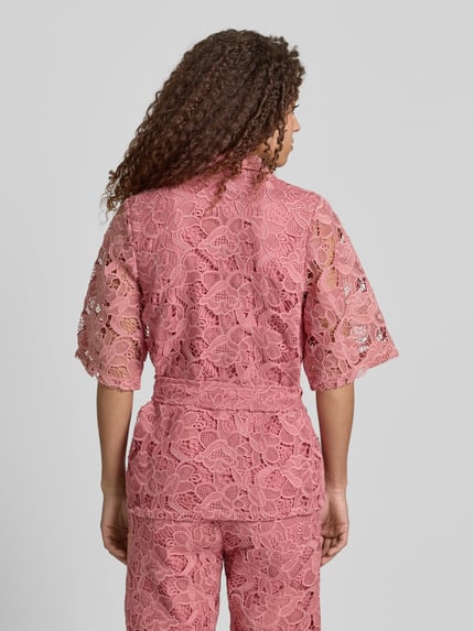 Vrouwenmodel draagt Bluse aus Spitze mit Bindegürtel van Jake*s collectie, roze kant, getailleerd model, kentkraag, knoopsluiting, strikceintuur, ruglengte maat 36: 70 cm, mouwlengte maat 36: 34 cm, geheel achteraanzicht.