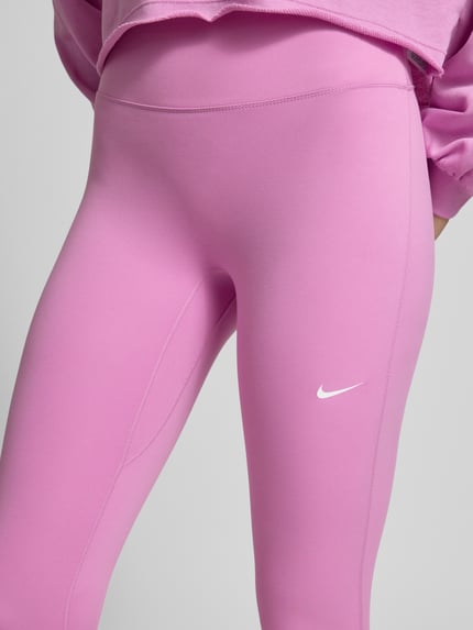 Frauenmodel trägt Leggings mit Logo-Print Modell 'One' von NIKE TRAINING in Pink, Material-Mix mit Stretch-Anteil, Nahaufnahme Oberkörper.