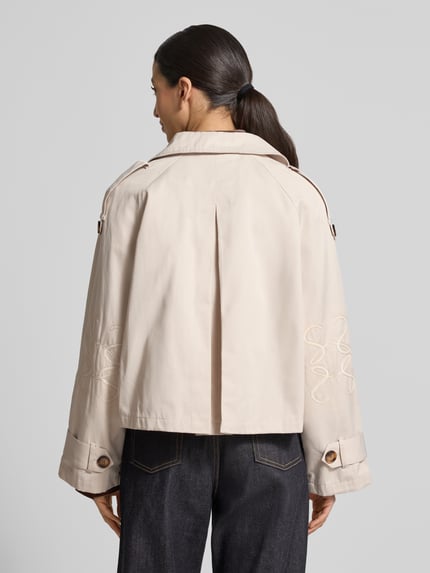 Frauenmodel trägt Kurzer Trenchcoat mit Eingrifftaschen von Smith and Soul aus Baumwoll-Mix, kurze Passform, zweireihig, Umlegekragen, Rückenlänge 55 cm, Schulterbreite 43 cm, Brustweite 62 cm, Ärmellänge 60 cm, helle Farbe, strukturierter Stoff, Ganzkörperansicht Rückansicht.