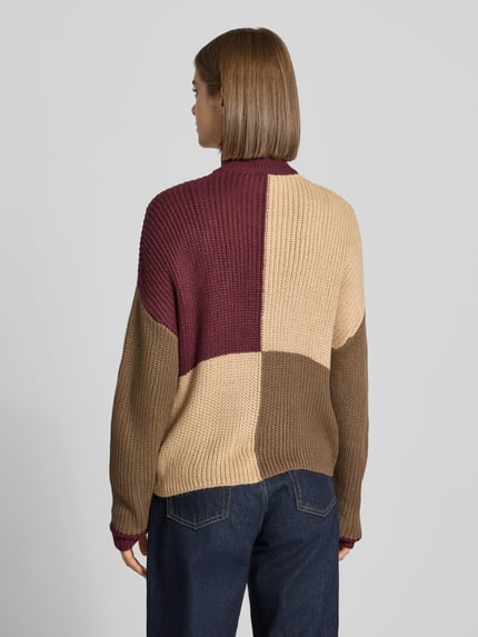 Frauenmodel trägt Jacke in Strick-Optik Modell 'Charlie' von NOISY MAY, Farbblöcke in Beige, Braun, Bordeaux, lockere Passform, Ganzkörperansicht Rückansicht.