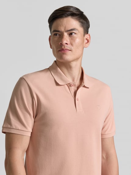 Męski model nosi Slim Fit Poloshirt mit Stitching von Jack & Jones Premium z bawełny, krój slim fit, haft, listwa guzikowa, nahaufnahme górnej części ciała