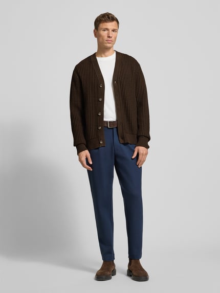 Männermodel trägt Regular Fit Strickjacke aus reine katoen Modell 'TOM' van SELECTED HOMME in bruin met wafelstructuur en knoopsluiting, unicolor, grofgebreid, geribde boorden, lange mouwen, ronde hals, Ganzkörperansicht van voren.