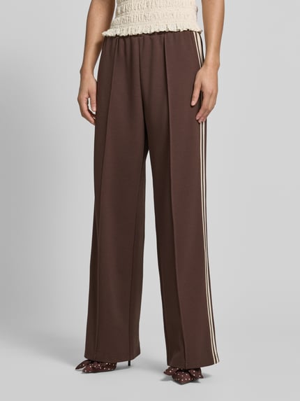 Frauenmodel trägt Jog Pants mit französischen Eingrifftaschen von Jake*s Casual in Braun, Wide-Leg-Fit, Material-Mix mit Stretch-Anteil, Elastischer Bund, Detailaufnahme Vorderseite.