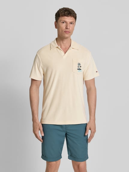 Mannenmodel draagt Regular Fit Poloshirt aus Frottee van Tommy Hilfiger, crèmekleurige badstof, borstzak, label stitching, polokraag, ganzkörperaanzicht van voren.