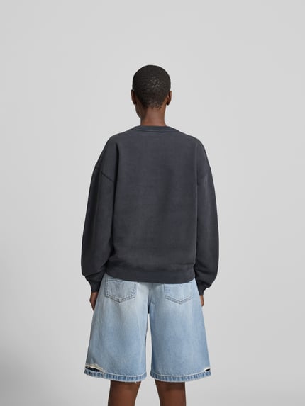 Männermodel trägt Regular Fit Sweatshirt mit Motiv-Print von Anine Bing, czarna bawełna, krój regular fit, ściągacze, widok całej sylwetki z tyłu
