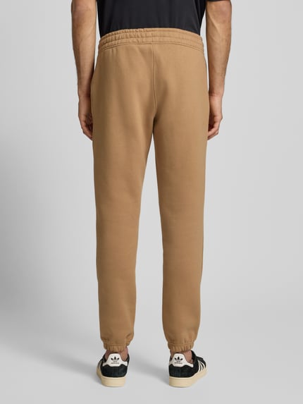 Męski model nosi Sweatpants mit elastischem Bund od adidas Originals, luźny krój, bawełniany miks, gumka w pasie, widok całej sylwetki z tyłu.