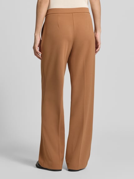 Männermodel trägt spodnie z szerokimi nogawkami Wide Leg Hose mit wpuszczane kieszenie model 'Hillda' von Stehmann, brązowy, gładka faktura, Ganzkörperansicht Rückansicht.