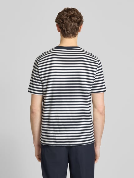 Męski model nosi Regular Fit T-Shirt aus reiner Baumwolle od Marc O'Polo, jersey w paski, kolor granatowo-biały, krótki rękaw, całkowity widok z tyłu.