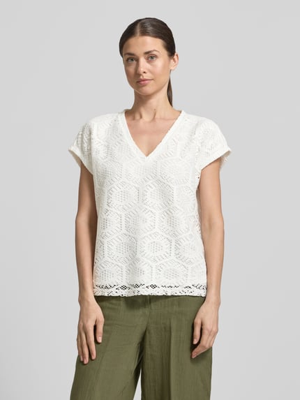 Kobiece model prezentuje damski t-shirt Boxy Fit T-Shirt mit semitransparentem Besatz Modell 'IRIS' od Vero Moda, efekt: jednolity kolor, wzór: abstrakcyjny, półprzezroczysty materiał jako obszycie, dekolt w serek, bez rękawów, wykończenie materiału: ażur, krój stretch, całkowity widok z przodu.