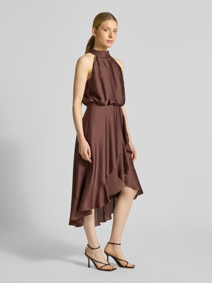 Modelka kobieca nosi Neckholder-Cocktailkleid mit Volants od Swing, satyna, krój A-linie, midikleid, kolor brązowy, szerokość w rozmiarze 36: 34 cm, długość tyłu 125 cm, widok całej sylwetki z przodu.